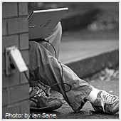 man using laptop in the corner behind the building 